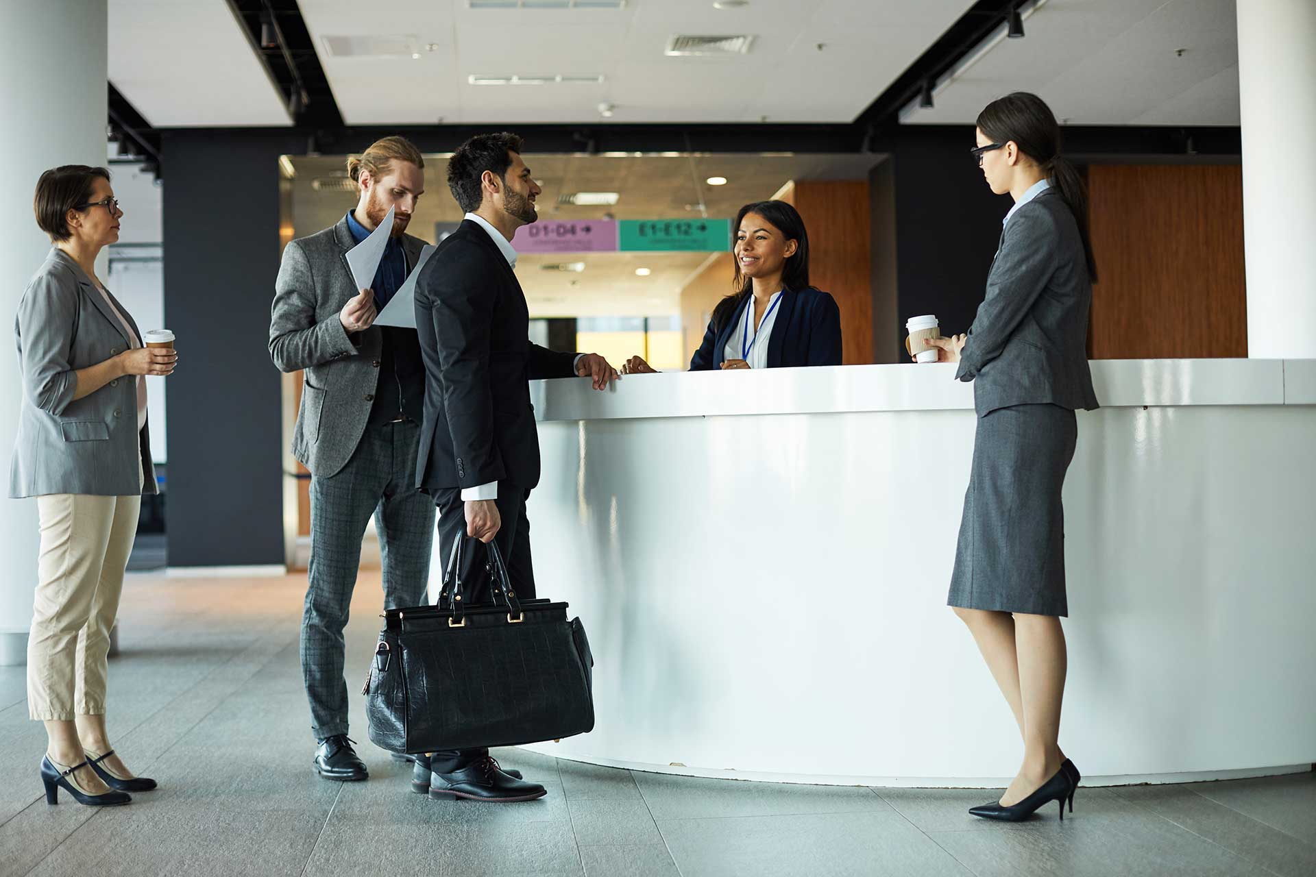 Group of professionals networking in a well-appointed hotel lobby, showcasing the vibrant and conducive environment created by Broadband Hospitality's technology solutions.